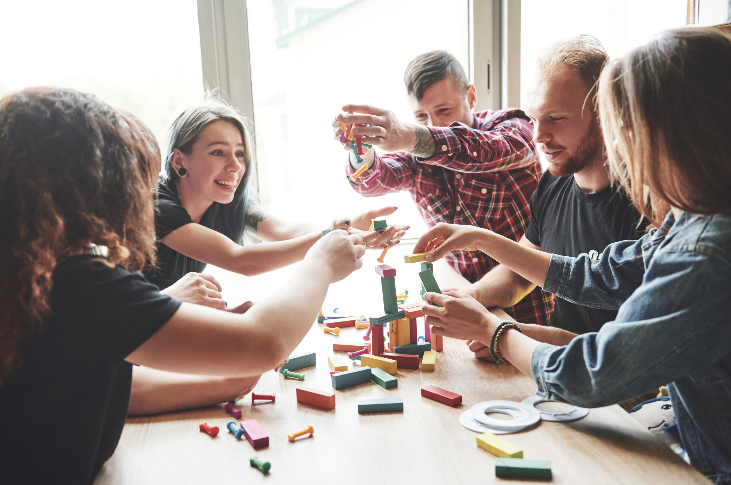 A group of creative friends sitting on a wooden table. People were having fun while playing a board game